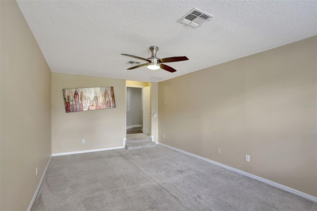 carpeted spare room with ceiling fan and a textured ceiling