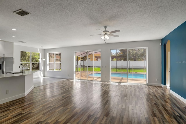 unfurnished living room with ceiling fan, a textured ceiling, sink, and dark hardwood / wood-style flooring