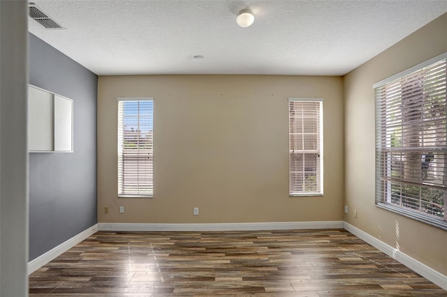 spare room with a textured ceiling and dark hardwood / wood-style flooring