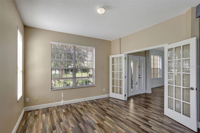 unfurnished room featuring a wealth of natural light, dark wood-type flooring, and french doors