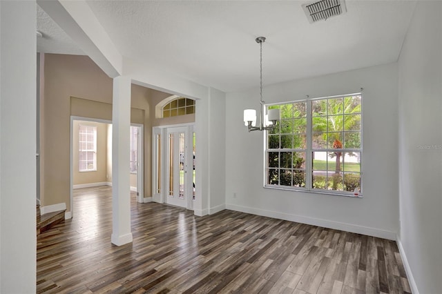 interior space featuring an inviting chandelier, a textured ceiling, and dark wood-type flooring