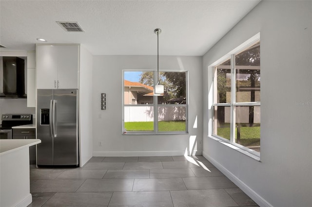 unfurnished dining area featuring plenty of natural light, dark tile patterned flooring, and a textured ceiling