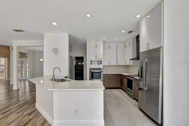 kitchen with white cabinetry, light hardwood / wood-style flooring, sink, appliances with stainless steel finishes, and a textured ceiling