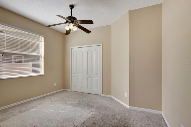 unfurnished bedroom with light carpet, a closet, a textured ceiling, and ceiling fan