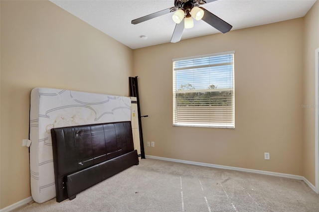 carpeted bedroom featuring ceiling fan and a textured ceiling