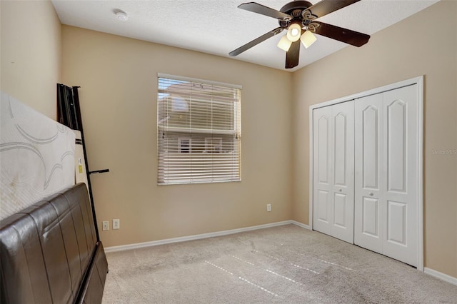 carpeted bedroom with ceiling fan, a textured ceiling, a closet, and multiple windows