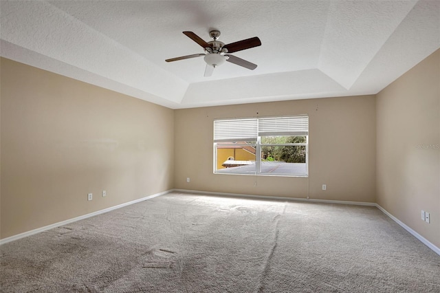 spare room with ceiling fan, a tray ceiling, a textured ceiling, and carpet flooring