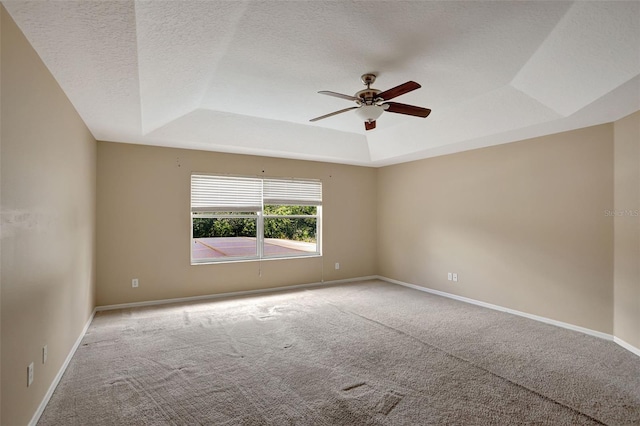 carpeted spare room with a textured ceiling, ceiling fan, and a raised ceiling