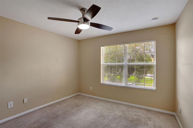 spare room featuring light carpet, ceiling fan, and a textured ceiling