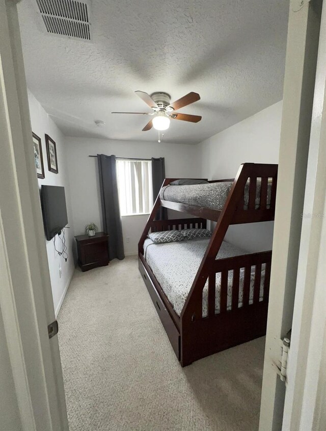 bedroom with a textured ceiling, ceiling fan, and light carpet