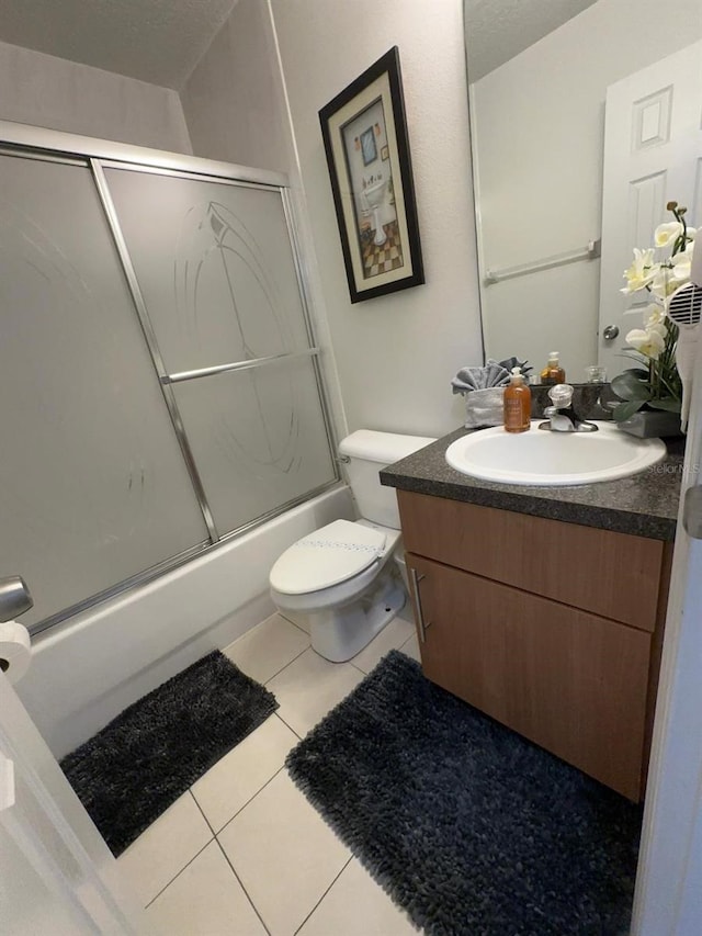 full bathroom featuring tile patterned flooring, combined bath / shower with glass door, vanity, and toilet