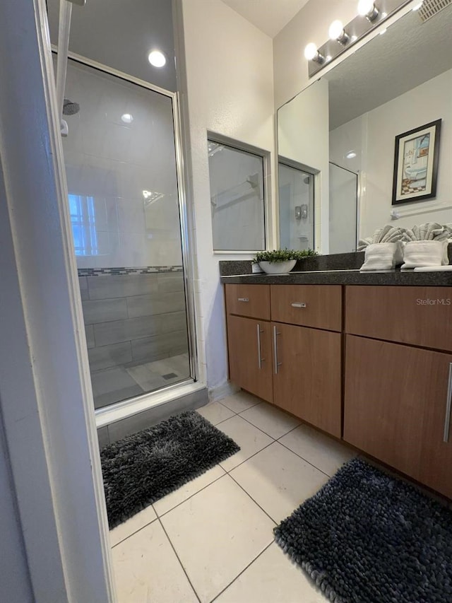 bathroom with tile patterned flooring, walk in shower, and vanity