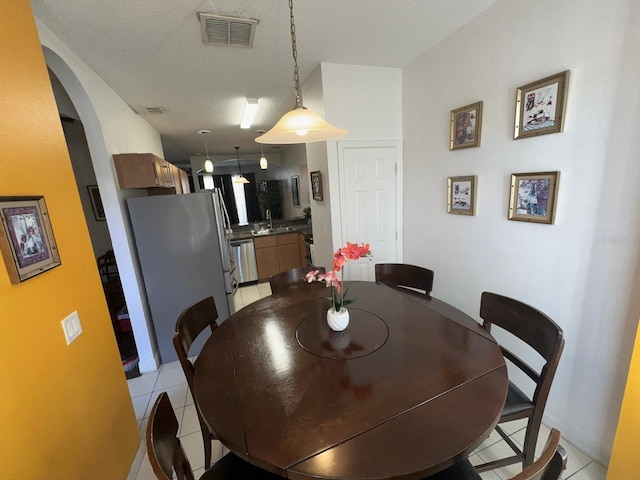 dining room with a textured ceiling, sink, and light tile patterned floors