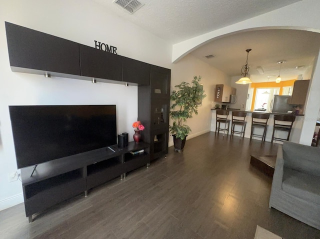 living room with a textured ceiling and dark hardwood / wood-style floors