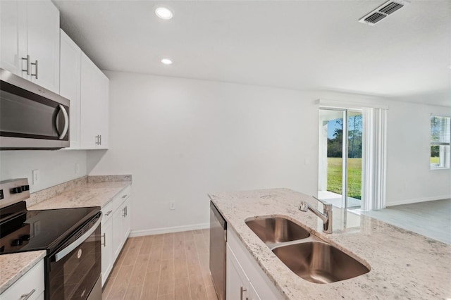 kitchen with light hardwood / wood-style floors, sink, appliances with stainless steel finishes, light stone countertops, and white cabinets