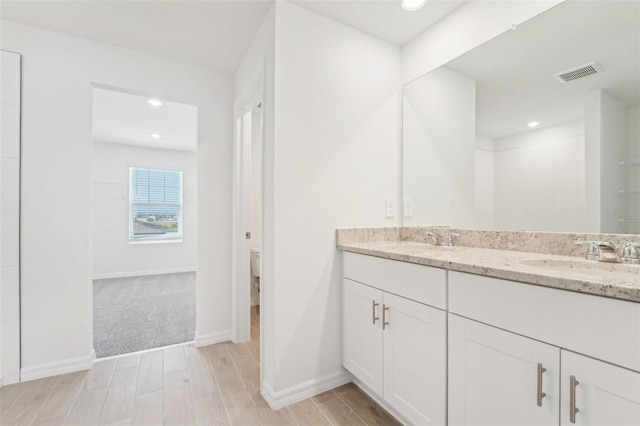 bathroom with toilet, vanity, and wood-type flooring