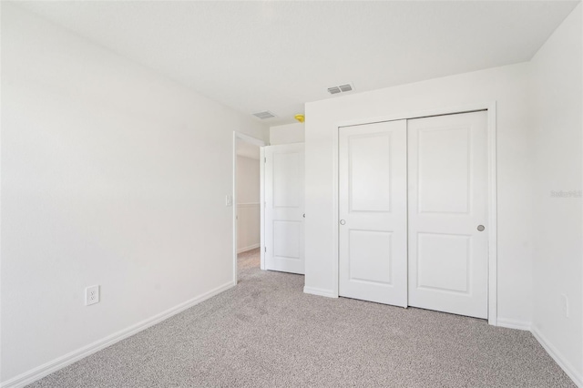 unfurnished bedroom with light colored carpet and a closet