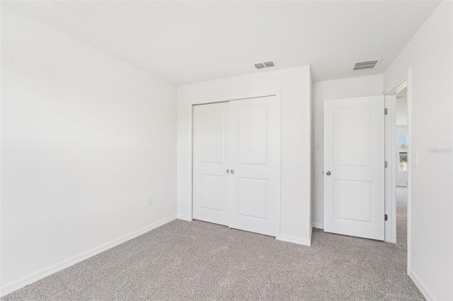 unfurnished bedroom featuring light carpet and a closet