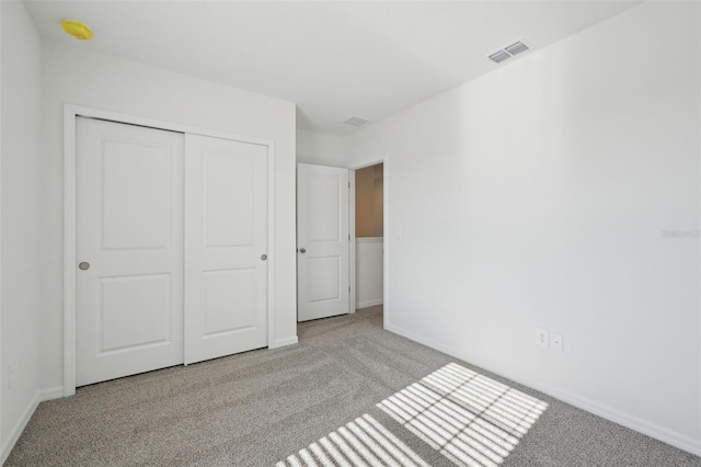 unfurnished bedroom with light carpet and a closet