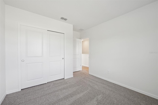 unfurnished bedroom with a closet and light colored carpet