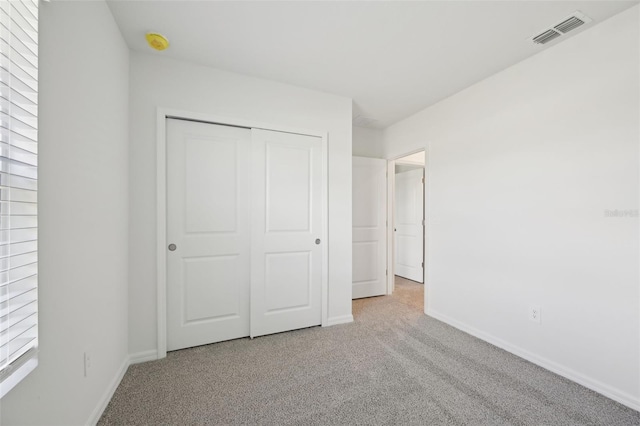 unfurnished bedroom featuring light colored carpet and a closet