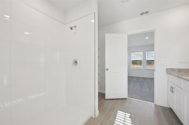 bathroom with tiled shower and vanity