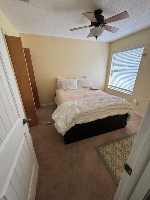 carpeted bedroom with ceiling fan and a textured ceiling