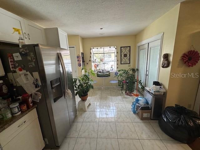 kitchen with white cabinets, stainless steel fridge with ice dispenser, and a textured ceiling