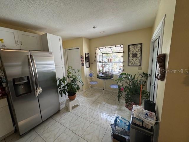 kitchen with white cabinets, stainless steel fridge with ice dispenser, and a textured ceiling