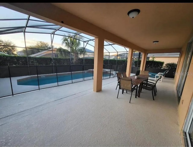 patio terrace at dusk with a fenced in pool and a lanai