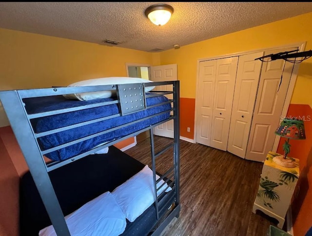 bedroom featuring dark hardwood / wood-style flooring, a textured ceiling, and a closet