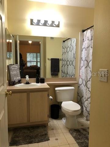 bathroom featuring tile patterned flooring, a shower with curtain, vanity, and toilet