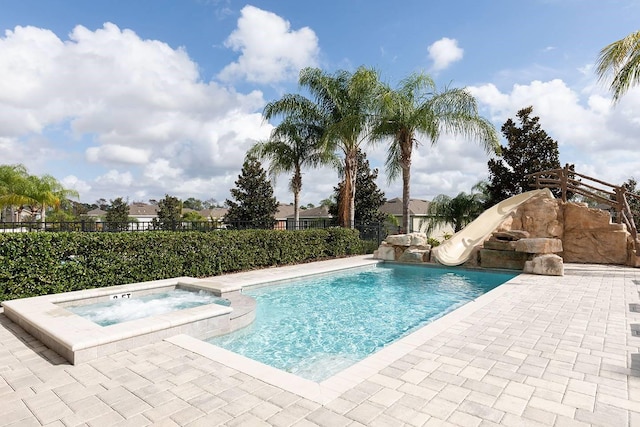 view of swimming pool with an in ground hot tub and a water slide