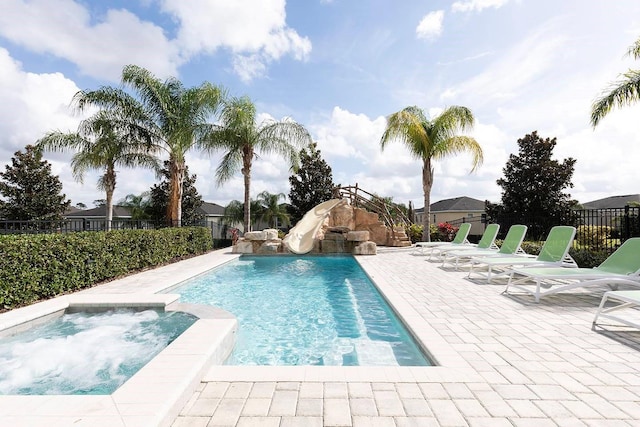 view of pool featuring an in ground hot tub, a water slide, and a patio area