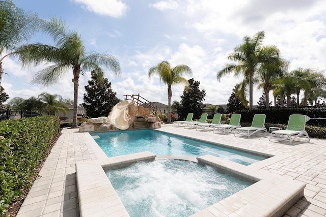 view of pool featuring a patio, a water slide, and an in ground hot tub