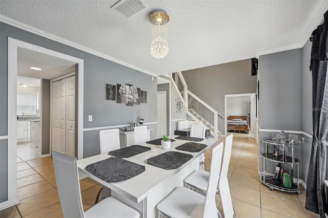 dining area featuring crown molding, light tile patterned floors, and a textured ceiling