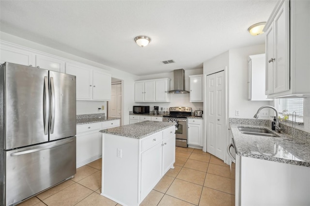 kitchen with wall chimney range hood, a kitchen island, sink, white cabinets, and appliances with stainless steel finishes