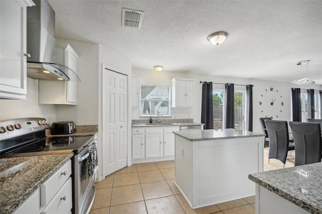 kitchen with wall chimney exhaust hood, stone countertops, stainless steel appliances, a center island, and white cabinetry