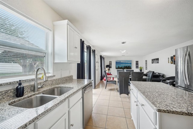 kitchen featuring sink, light stone countertops, appliances with stainless steel finishes, light tile patterned floors, and white cabinetry