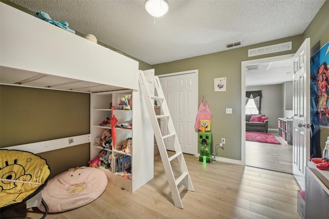 bedroom with light wood-type flooring, a closet, and a textured ceiling