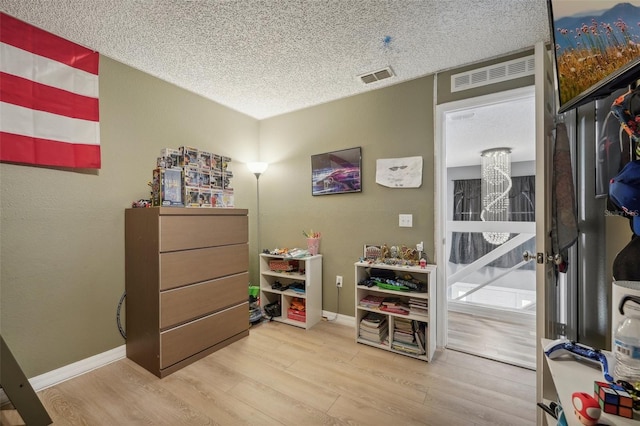 misc room with a textured ceiling and light hardwood / wood-style floors