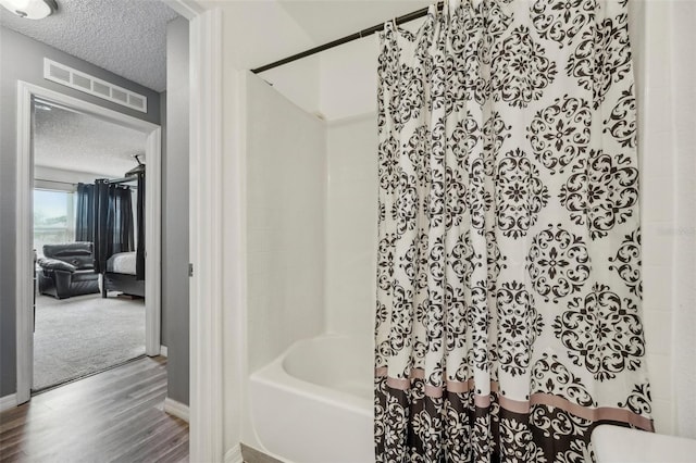 bathroom featuring wood-type flooring, a textured ceiling, and shower / bathtub combination with curtain