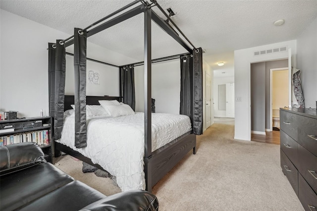 bedroom featuring light colored carpet and a textured ceiling