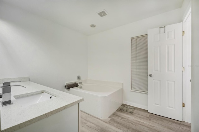 bathroom with vanity, hardwood / wood-style flooring, and a bath