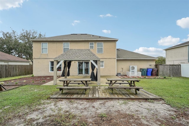 back of property with a yard, a wooden deck, and a patio