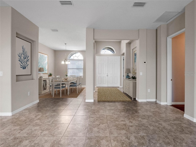 tiled entryway with a notable chandelier