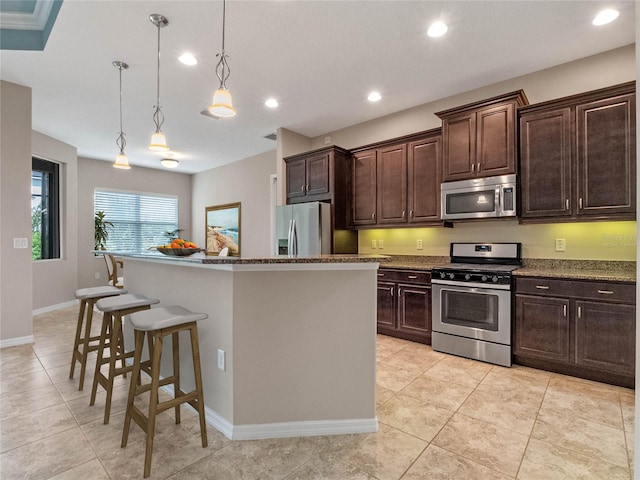 kitchen featuring dark brown cabinets, stainless steel appliances, a center island, a kitchen bar, and pendant lighting