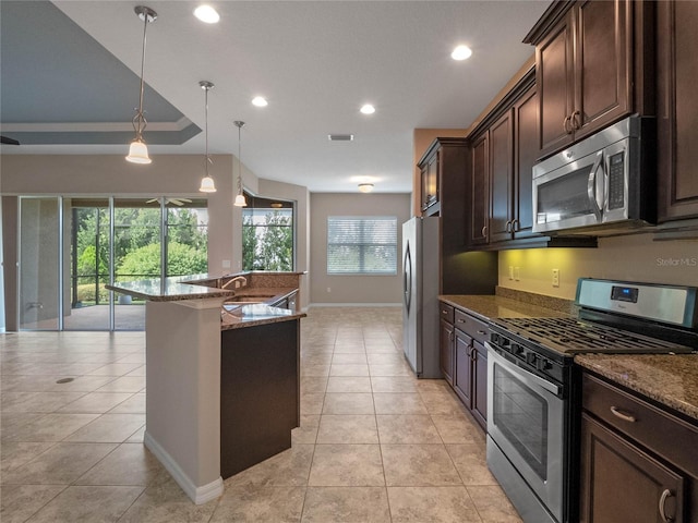 kitchen with dark brown cabinetry, stainless steel appliances, hanging light fixtures, and light stone counters