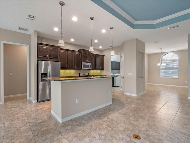 kitchen featuring appliances with stainless steel finishes, ornamental molding, dark brown cabinetry, and a center island with sink