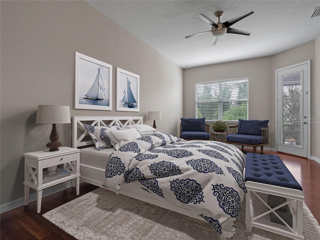 bedroom featuring ceiling fan, a textured ceiling, dark hardwood / wood-style flooring, and access to exterior